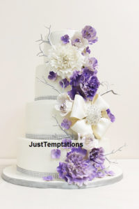 white 4 tiered cake with purple flower and twigs